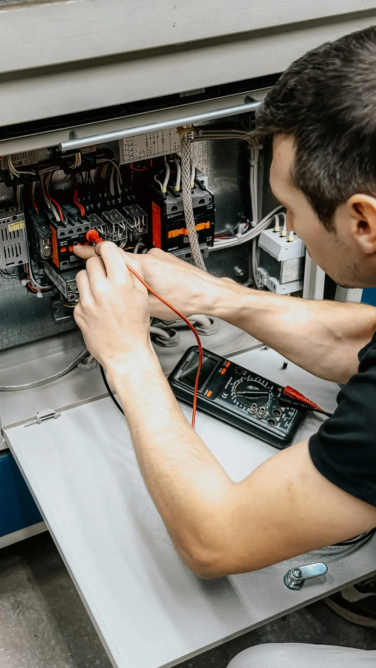 Un électricien en train de tester un tableau électrique avec un testeur